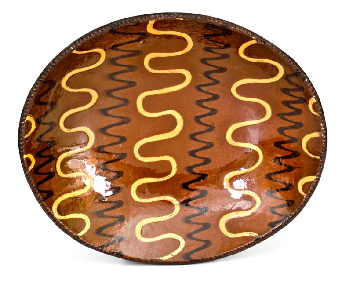 Outstanding Redware Platter with Profuse Yellow and: Redware Loaf Dish with Profuse Two-Color Slip Decoration, New England origin, early 19th century, oval form with coggled edge, the interior decorated with alternating wavy trails of manganese and crea