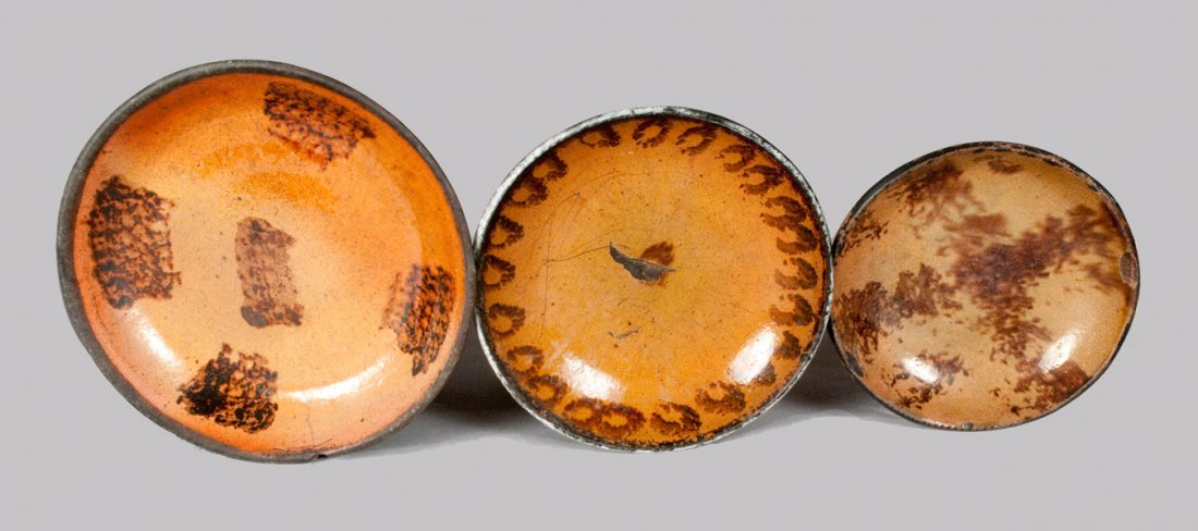 Lot of Three: Redware Dishes with Manganese Decoration: Three Redware Dishes with Sponged Manganese Decoration, Pennsylvania origin, second half 19th century, one with circular sponging around edge, one with four sponged blocks surrounding a block at the c