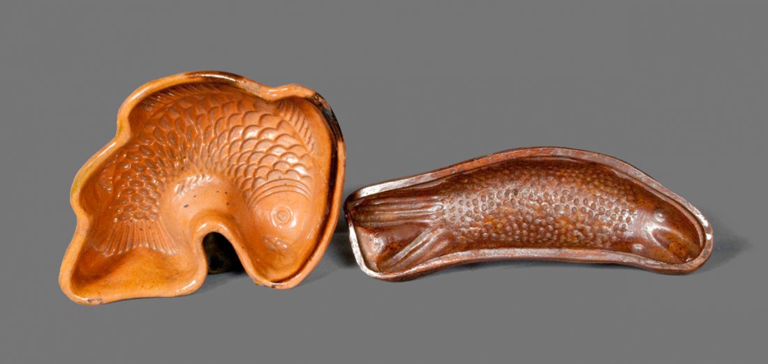 Lot of Two: Glazed Pennsylvania Redware Fish Molds: Two Glazed Redware Fish Molds, Pennsylvania origin, 19th century, one in the form of a curved fish with heavily-scaled body and manganese-highlighted edge; the other with a lead-and-manganese-glazed i
