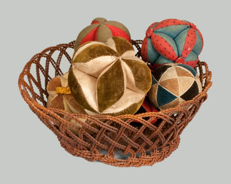 Group of Six Sewing Balls in Wire Basket, American, mid: Six Sewing Balls in Wire Basket, American, possibly Pennsylvania, mid to late 19th century, including five similarly-styled examples and one with triangular pattern. In a wire basket of undetermined a