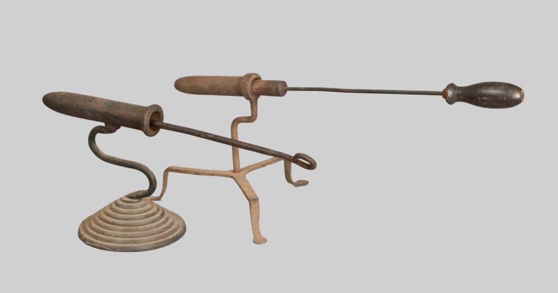 Two Wrought Iron Gophering Irons, 18th or early 19th ce: Two Wrought Iron Gophering Irons, 18th or early 19th century, one with stepped circular base and curved stem, original wooden handle; paired with a tripod-based example, the iron with circular handle 