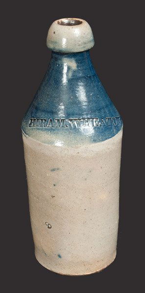 Stoneware Bottle with Bright Blue-Dipped Top Dated 1875: Cobalt-Dipped Stoneware Bottle, Stamped "HIRAM.WHEATON / 1875," Northeastern U.S. origin, cylindrical bottled with tapered, semi-rounded spout, the interior neck covered in bright cobalt slip. Front i