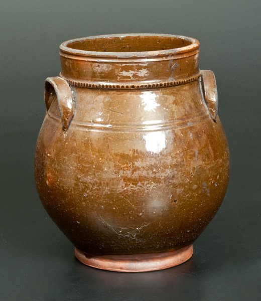 New England Ovoid Redware Handled Jar: Glazed Redware Jar, New England origin, second quarter 19th century, ovoid jar with footed base, applied lug handles, and coggled molding at base of collar, decorated with light manganese highlights a