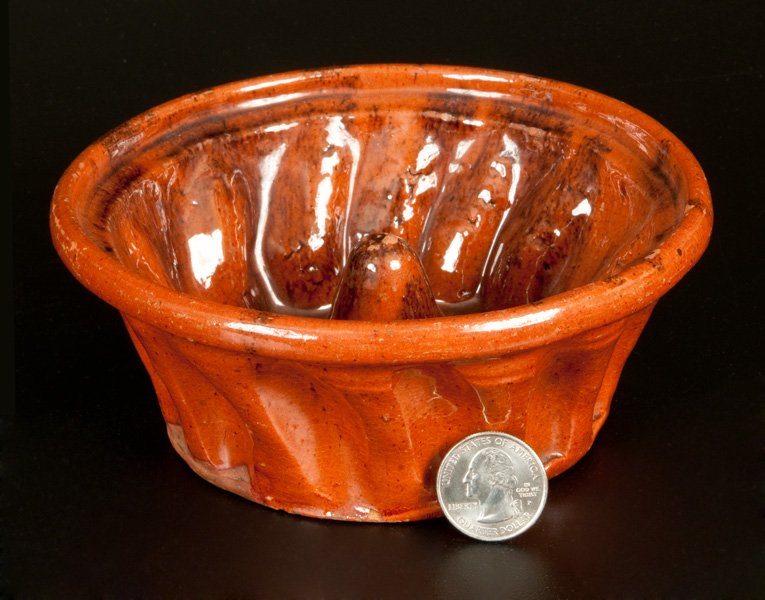 Small-Sized Redware Mold with Sponged Manganese: Glazed Redware Food Mold, PA origin, second half 19th century, circular mold with raised patterning, rounded rim, and manganese sponging on interior. Two small chips to bottom edge. Light wear to rim.