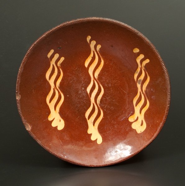 Redware Plate with Yellow Slip Decoration: Slip-Decorated Redware Plate, American, 19th century, with coggled edge, the interior decorated with three groups of wavy yellow slip stripes. Provenance: A fresh-to-the-market example from a long-ter