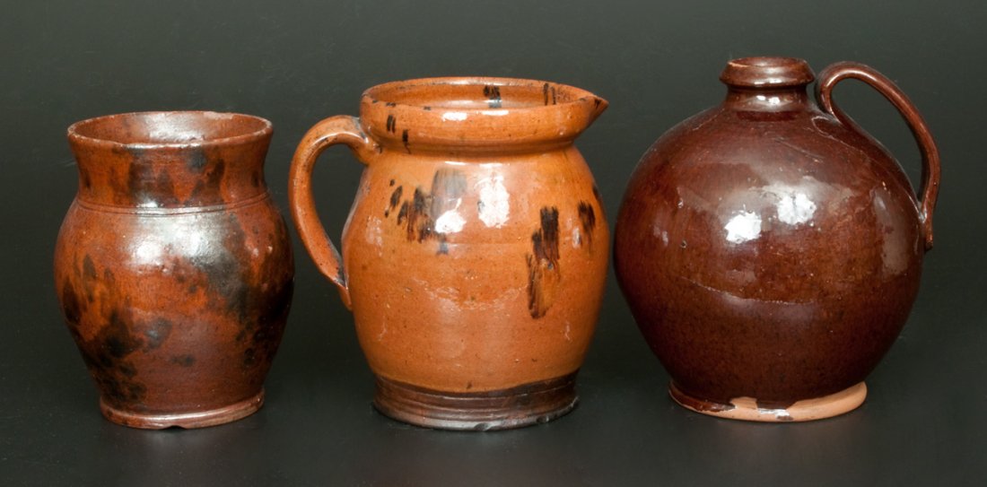 Lot of Three: Glazed Redware Vessels: Three Glazed Redware Articles, American, 19th century, a lead-glazed ovoid pitcher with manganese accents; an ovoid jug with lead-and-manganese glaze; and a lead-glazed ovoid jar with splashed mangane