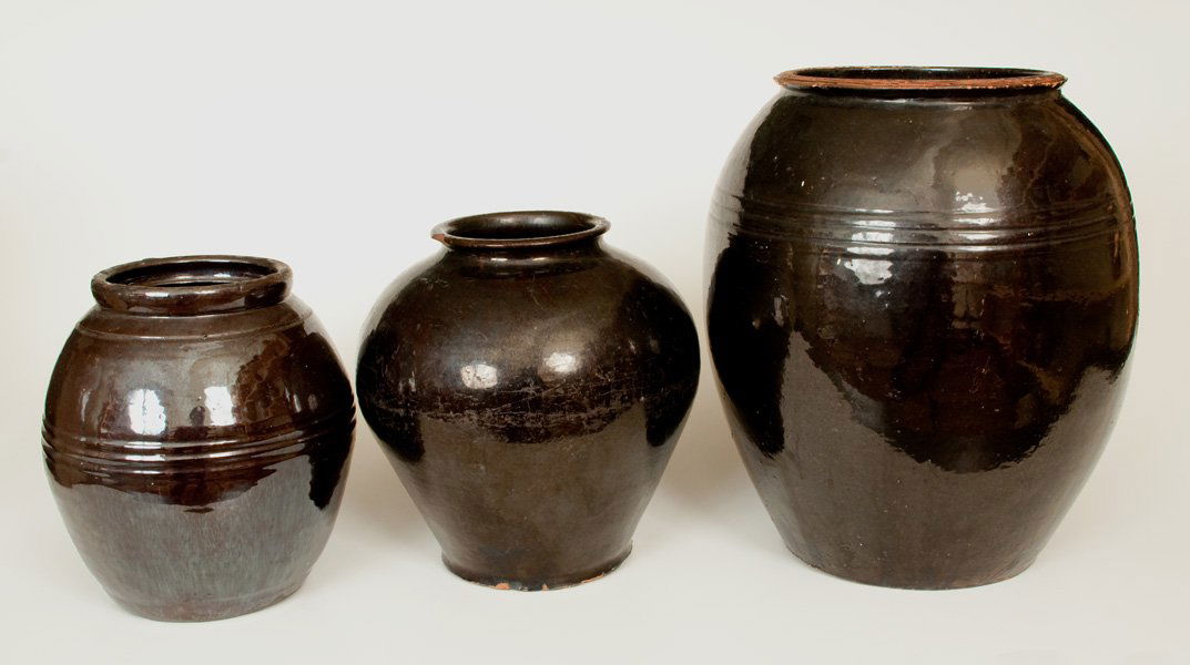 Lot of Three: Large Ovoid Manganese-Glazed Redware Jars: Three Glazed Redware Jars, 19th century, all of ovoid form, with lead-and-manganese-glazed surfaces. Largest jar with nicks and wear to rim. Middle-sized jar with rim chips, small base chips, some wea