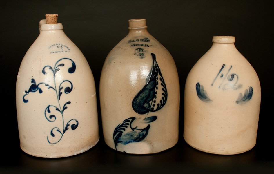 Lot of Three: Stoneware Jugs incl. Rare WILLIAM KELLEY: Three Stoneware Jugs, Northeastern U.S. origin, 19th century, a two-gallon jug with cobalt floral decoration, stamped "PORTER & FRASER / WEST TROY, N.Y."; a two-gallon jug with cobalt leaf decoration,