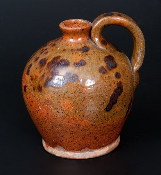 Diminutive Redware Jug with Manganese Splotches: Diminutive Ovoid Redware Jug with Manganese Decoration, probably Pennsylvania origin, 19th century, highly-ovoid jug with footed base, ribbed strap handle, and flared spout, decorated with splashed ma