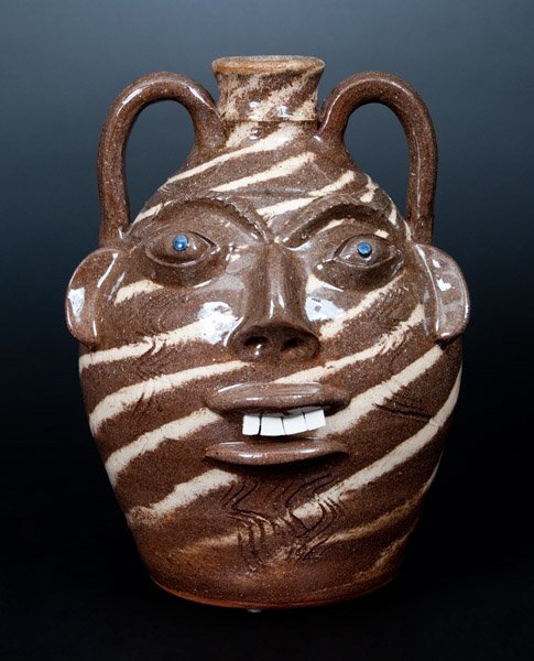 Walter Fleming Stoneware Swirl Face Jug: Swirl-Glazed Stoneware Face Jug, Stamped "Walter P. Fleming," North Carolina origin, wheel-thrown jug with double handles and applied face with blue eyes, porcelain teeth, and combed accents, the surf