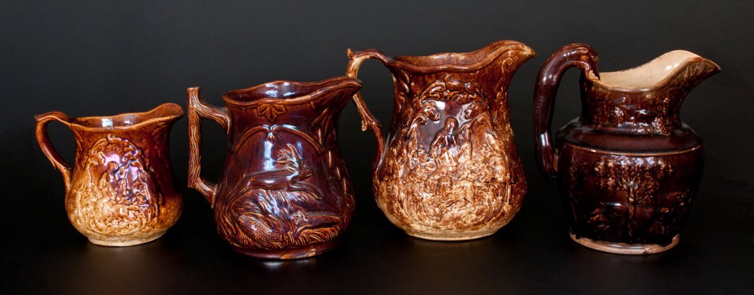 Lot of Four: Rockingham Ware Pitchers, Baltimore and: Four Rockingham Pottery Pitchers, American, third quarter 19th century, one depicting Daniel Boone with hunting dog and game, the mold made by Charles Coxon for Edwin Bennett of Baltimore, MD; another