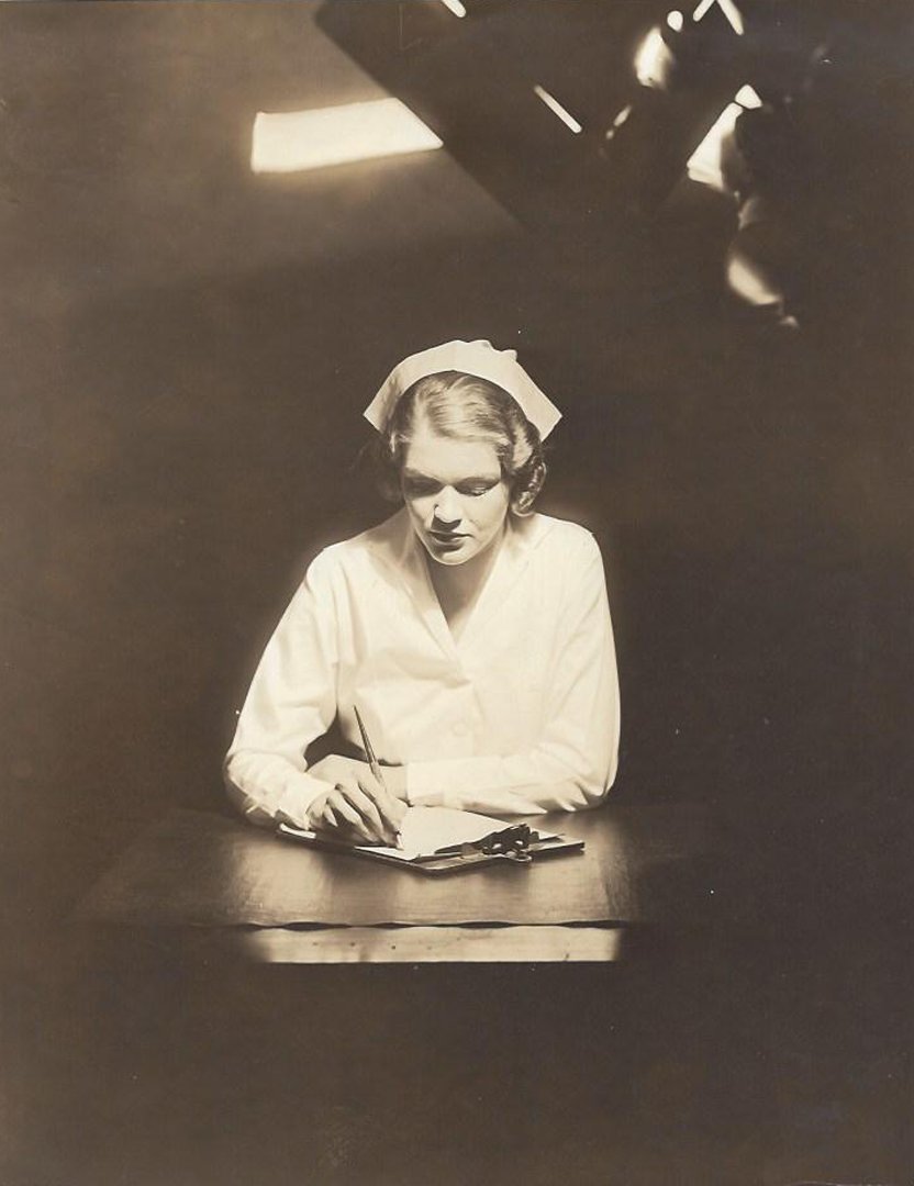 1920s Nurse.: Black and white photograph by Joel Feder of a nurse writing at a desk. Medium: silver print Measurements: 9 1/4 x 7 1/4
