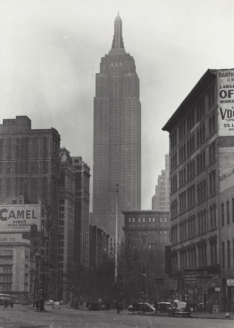 Attrib. Lou Stoumen, Empire State Building, 1940.: Attributed to Lou Stoumen (1917-1991), A black and white snapshot view of the Empire State Building towering above other buildings. Photographer: Attrib. to Lou Stoumen. Medium: Silver print. Measurem