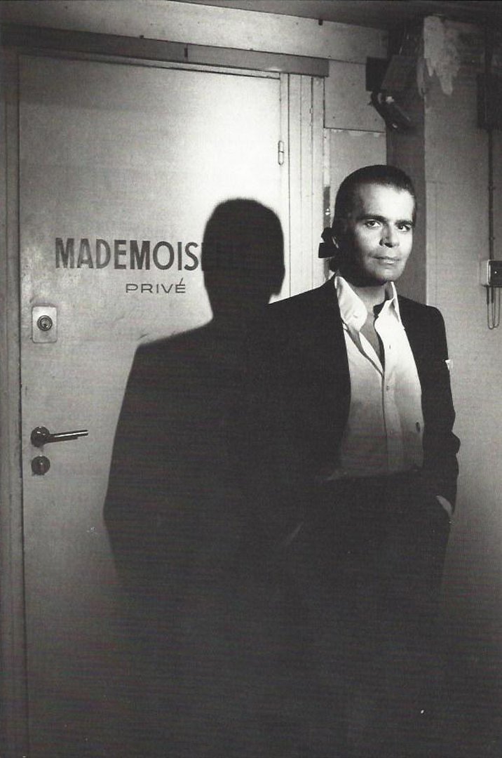 Karl Lagerfeld, Paris.: Karl Lagerfeld standing against the back door to Chanel. The door says Mademoiselle Prive. Mounted on board. Half-tone print. Unsigned. Photographer: Helmut Newton Medium: Half-tone print. Measurement