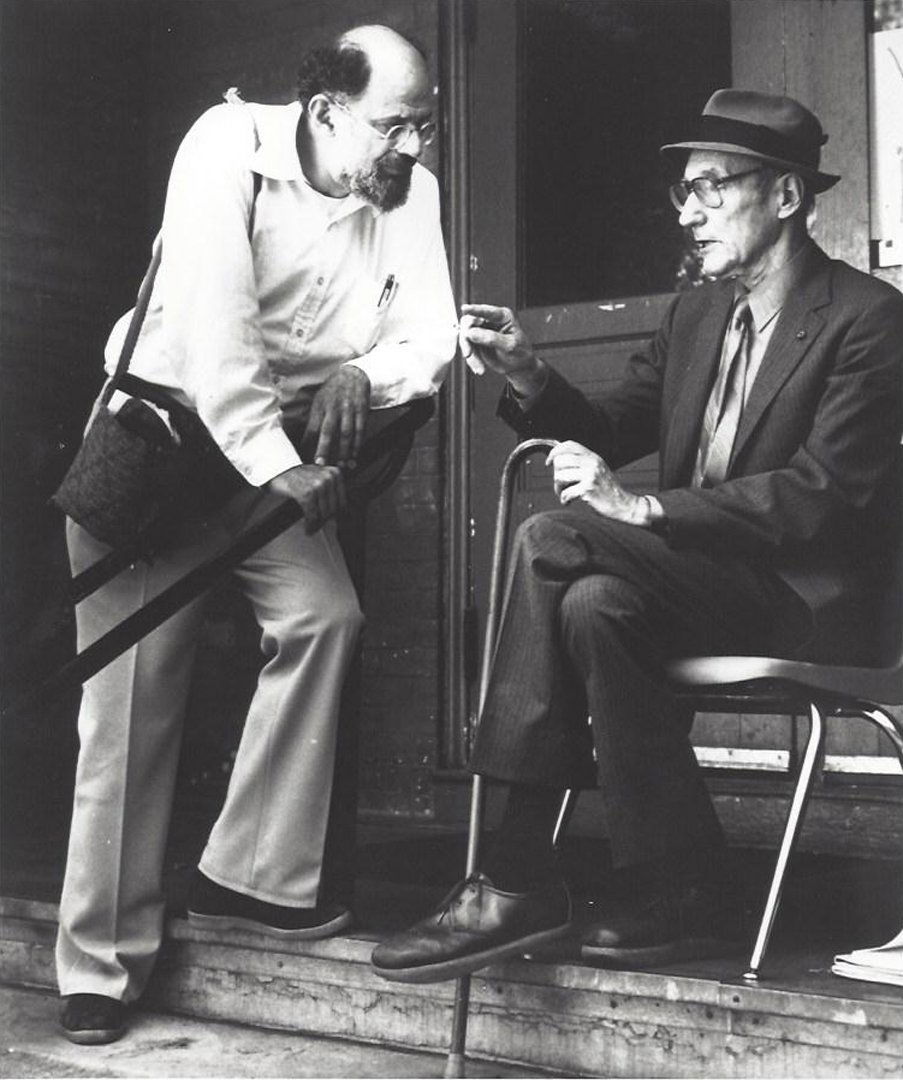 Still from "The Life and Times of Allen Ginsberg": Still from film "The Life and Times of Allen Ginsberg," 1993, directed by Jerry Aronson. Depicts Ginsberg on steps with William S. Burroughs. Photographic print. Press print. Unsigned. Exhibition labe