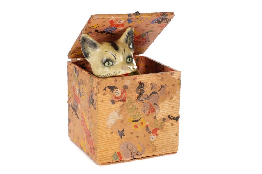 Papier Mache Cat Jack in the Box, 19th Century: Last quarter of 19th century. Early papier mache jack in the box with a cream colored cat with black accents and green eyes, open mouth on green and brown woven fabric draped spring in a whimsical car