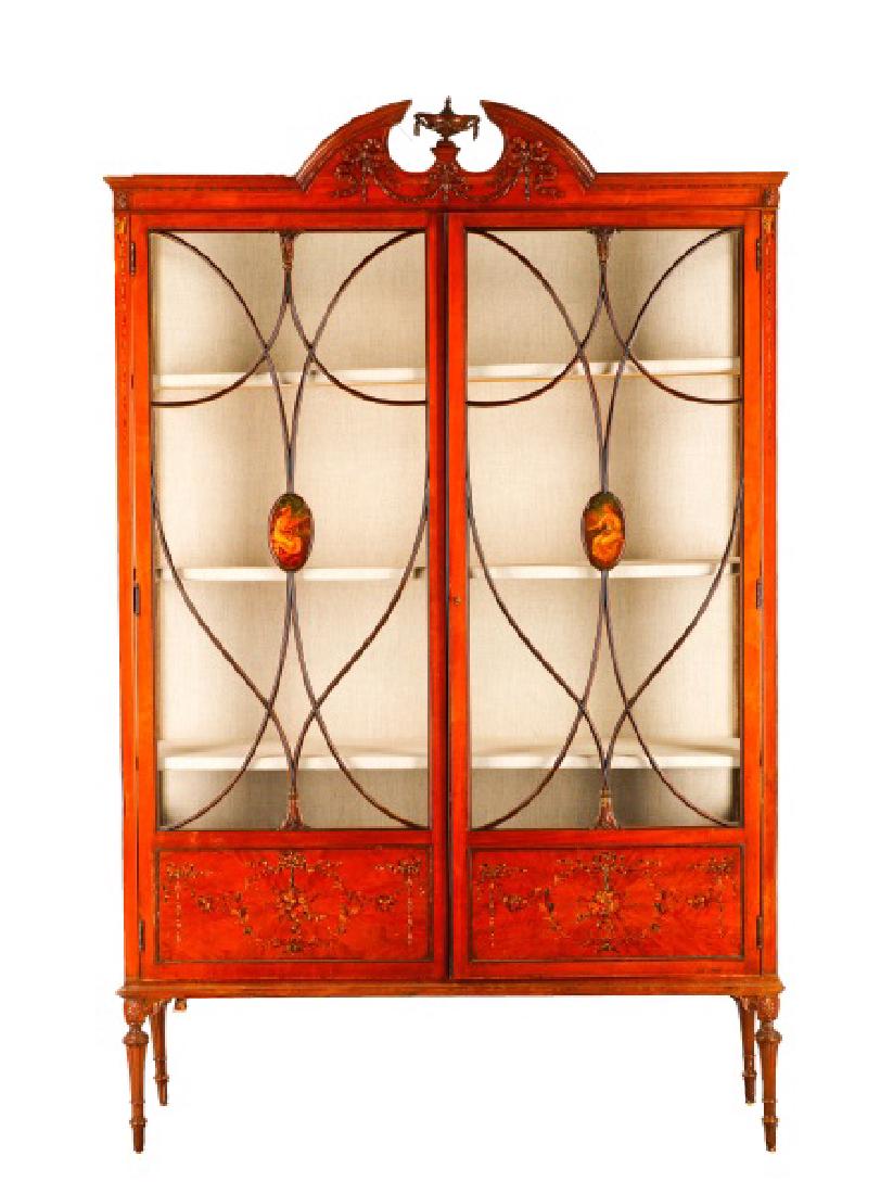 English Edwardian Satinwood Vitrine: English, late 19th/early 20th century. An Edwardian satinwood vitrine, having a crested broken pediment top with neoclassical motif carving, over two glass cabinet doors with elaborate scrolled mullio