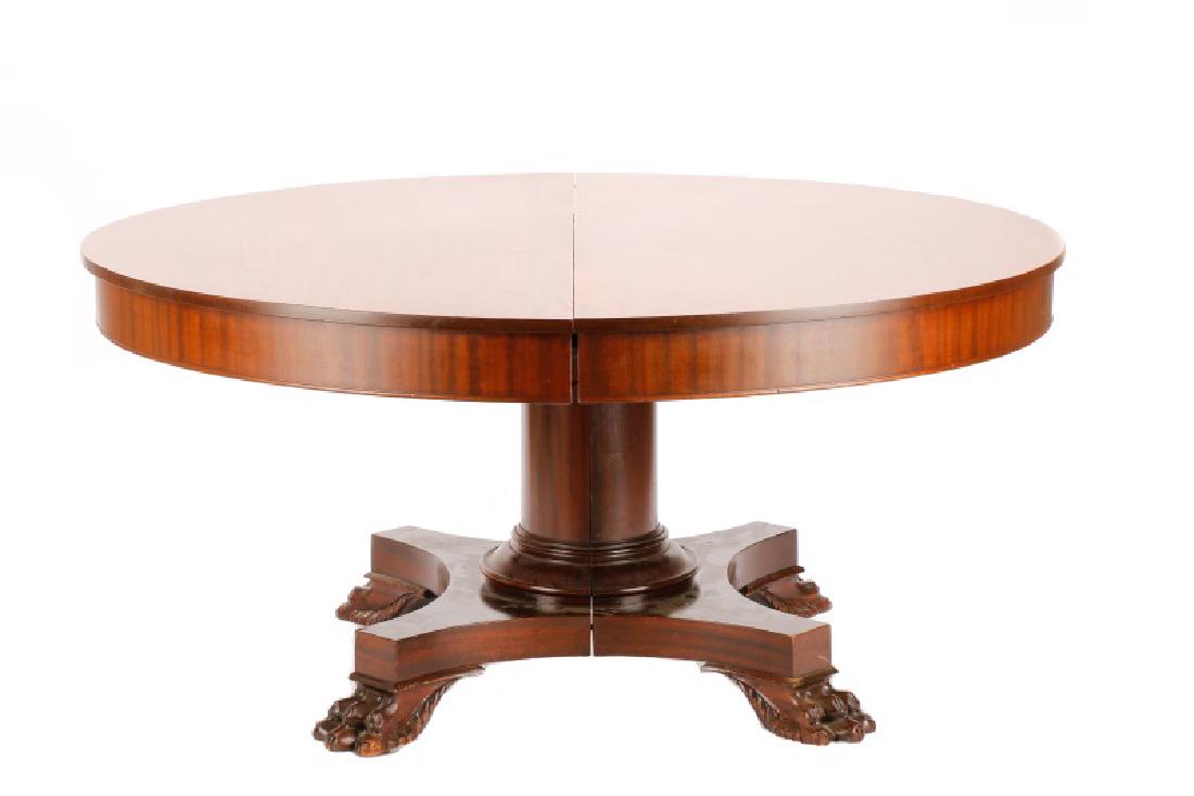 American Empire Revival Mahogany Dining Table: American, second half 19th century. An Empire Revival style mahogany dining table, having a round top resting on a columnar pedestal, on a shaped base with four hairy paw feet. Includes three leaves.