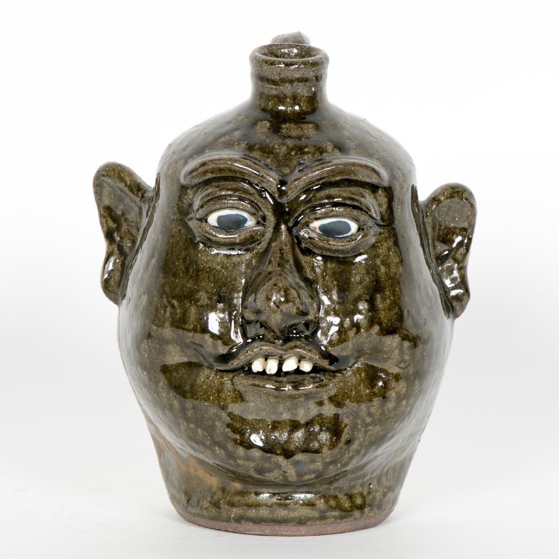 Lanier Meaders, Small Face Pottery Jug, Green: Lanier Meaders (Georgia, 1917-1998) Alkaline face jug with rock teeth Signed on underside Approx. h 9.5" Provenance: From the Lifetime Collection of Dick and Betty Hoepfinger, of Marietta, Georgia.