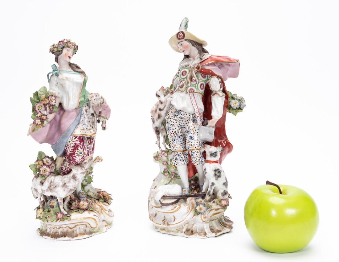 Pair, English Chelsea Bow Type Porcelain Figures: Late 18th to early 19th century, English; polychrome porcelain, well modeled figures of a shepherd and shepherdess with dogs and sheep; applied bocage florals; on rococo bases. Marked to back of base.