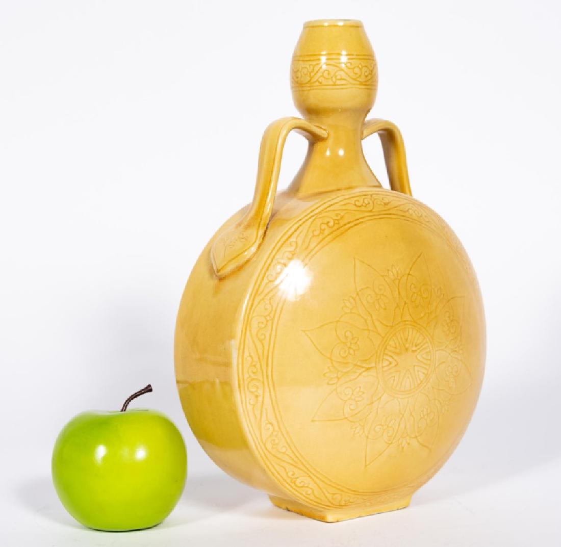 Chinese Yellow Ground Moon Flask Vase: Chinese; yellow ground porcelain having a swelled neck and body with applied curved handles; body with incised stylized floral decoration with lingzhi shaped petals. Unmarked. Approx. h. 12.125", w. 8