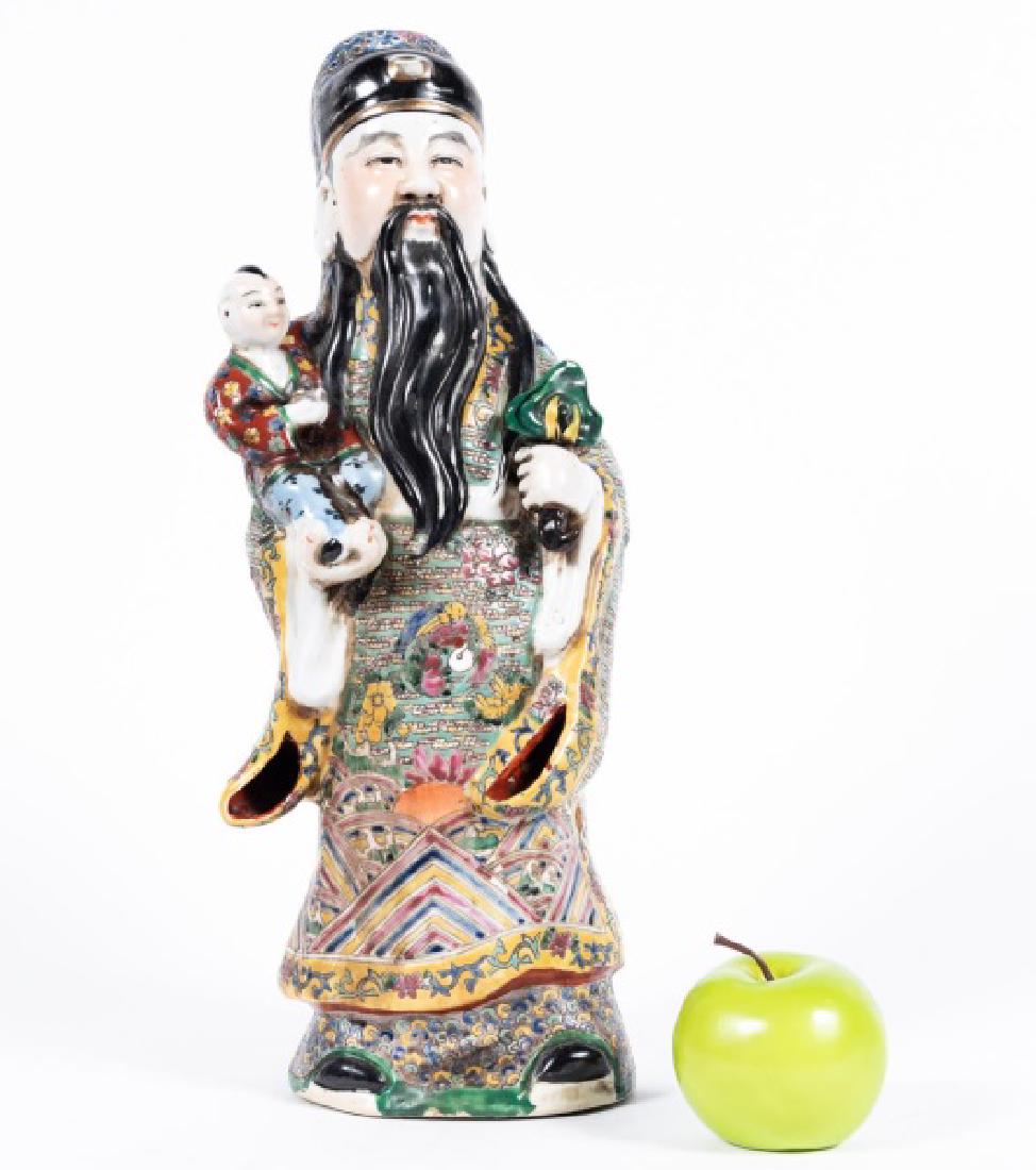 Chinese Standing Immortal Figure w/ Child: Chinese; polychrome porcelain with gilt accents; modeled as a robbed elder holding a small child. Impressed seal mark to the underside. Approx. h. 18.5". Provenance: From the Estate of Mr. Cecil S. Wh