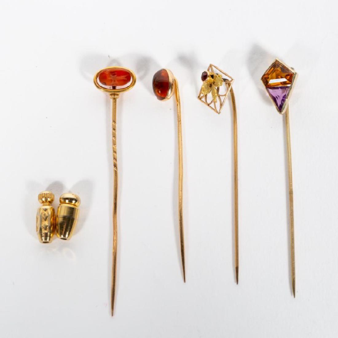 4 Yellow Gold Various Lapel Pins, Citrine: A group of four gold and semi precious stone stick pins, comprising of one roman intaglio stone, one cabochon citrine, one amethyst and citrine and one small garnet. Also includes two pin catches. One