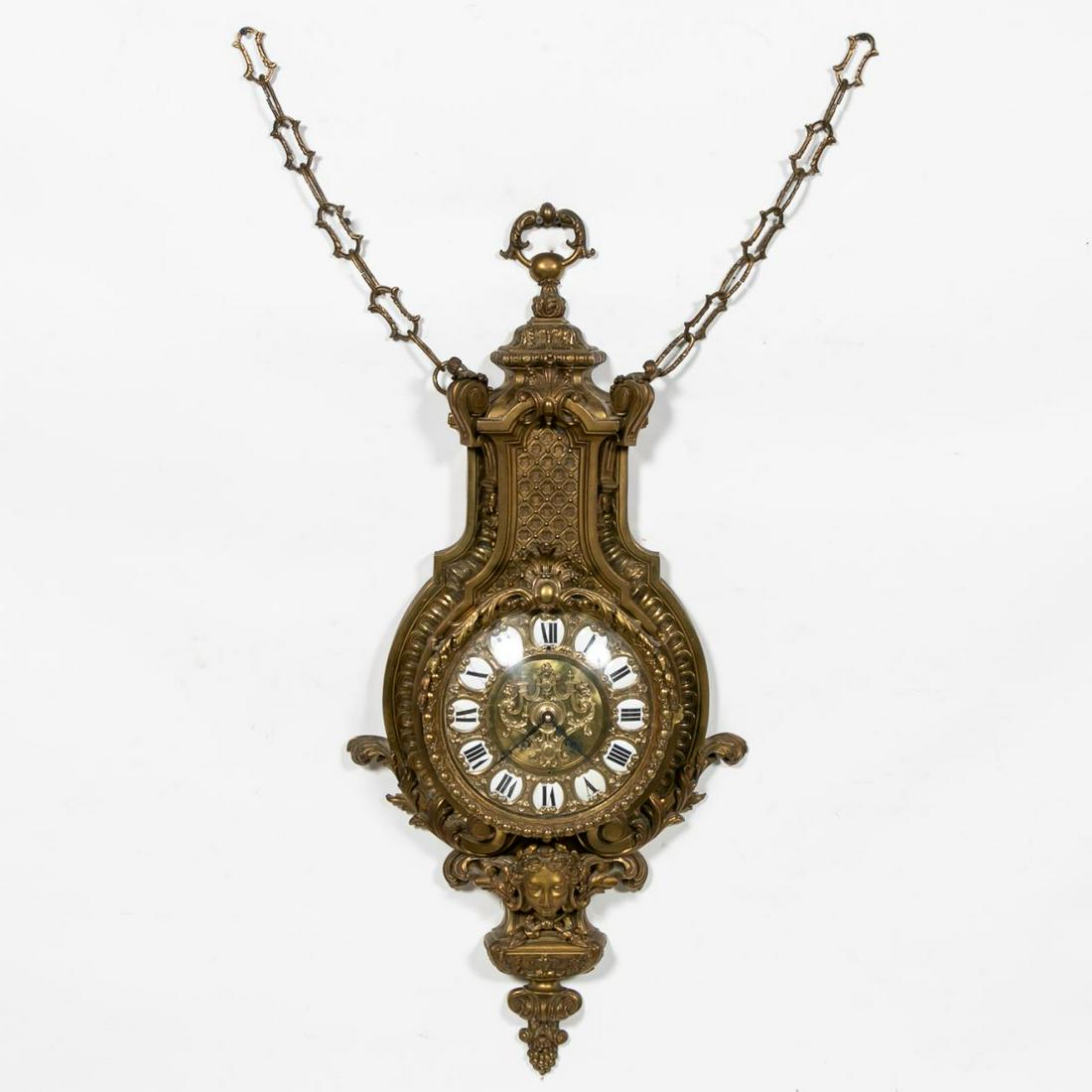 French Bronze Louis XV Style Cartel Clock: French, early 20th century. Cast bronze wall clock having a circular dial with enameled Roman numerals, the case with diapered and scrolled acanthus decoration above a female mask. Unmarked. Approx. h