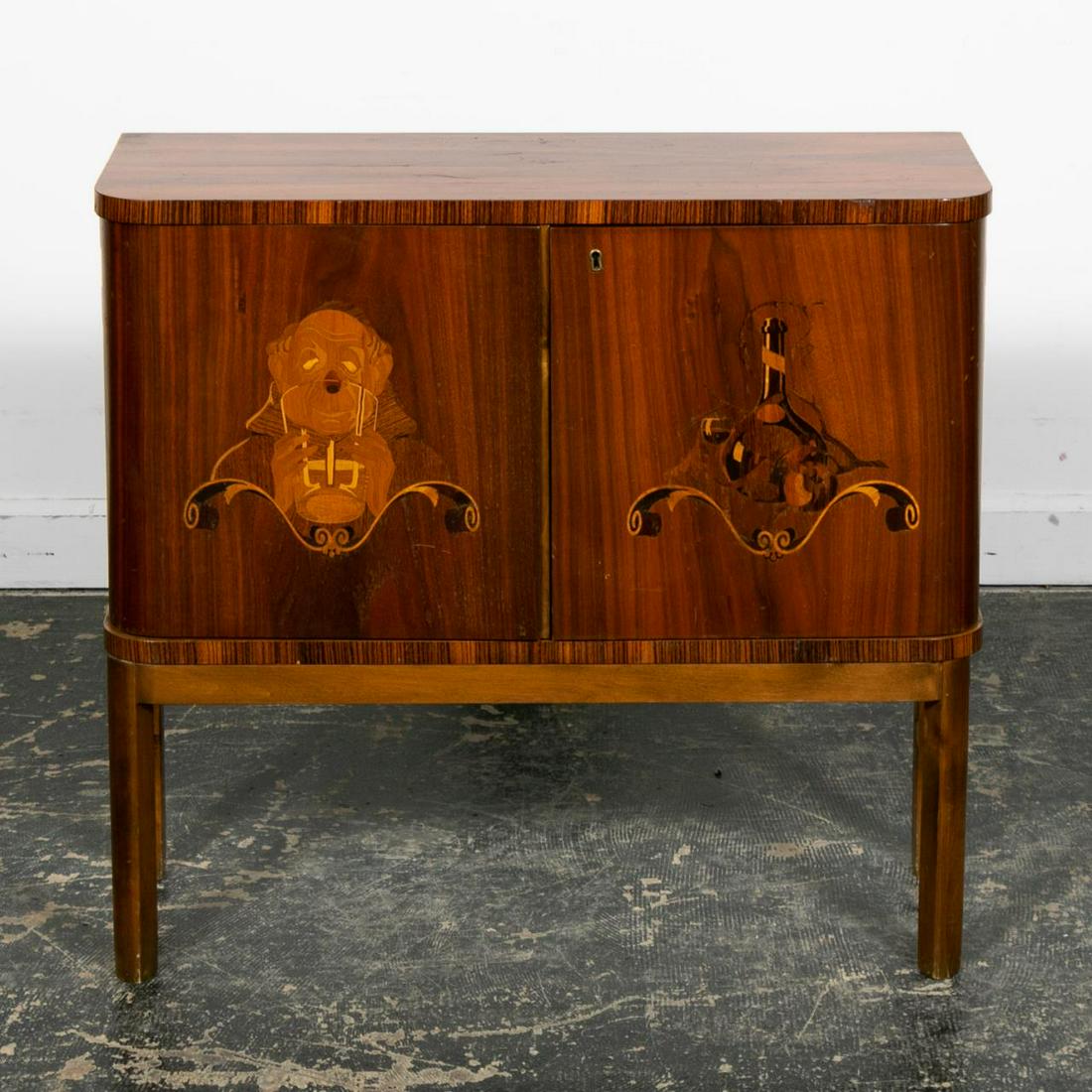 Continental Art Deco Inlaid Liquor Cabinet: Likely German or Austrian, second quarter 20th century. Small zebrawood marquetry "D" form bar or liquor cabinet on stand having double doors inlaid with a monk drinking and a bottle of wine with a gl