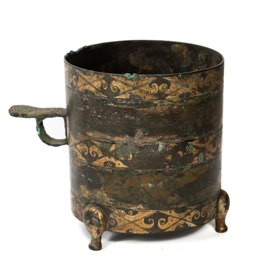 Chinese Western Han Dynasty Gilt Bronze Cup: Chinese, Han Dynasty. The cylindrical cup with single tab handle raised on three short feet, the body decorated with three horizontal gilt bands. Approx: h. 4.25". Provenance: From the Private Collect