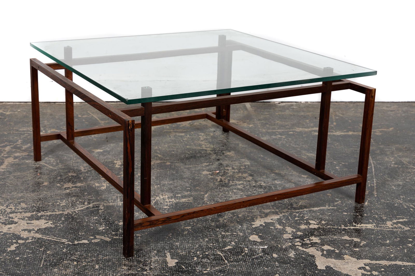 Henning Norgaard Rosewood Glass Coffee Table: Henning Norgaard (Danish, b. 1937- ) for Komfort (Danish, mid 20th century), circa 1960. A square glass top and rosewood coffee table. Approx. h. 16.5", w. 31.5", d. 31.5".