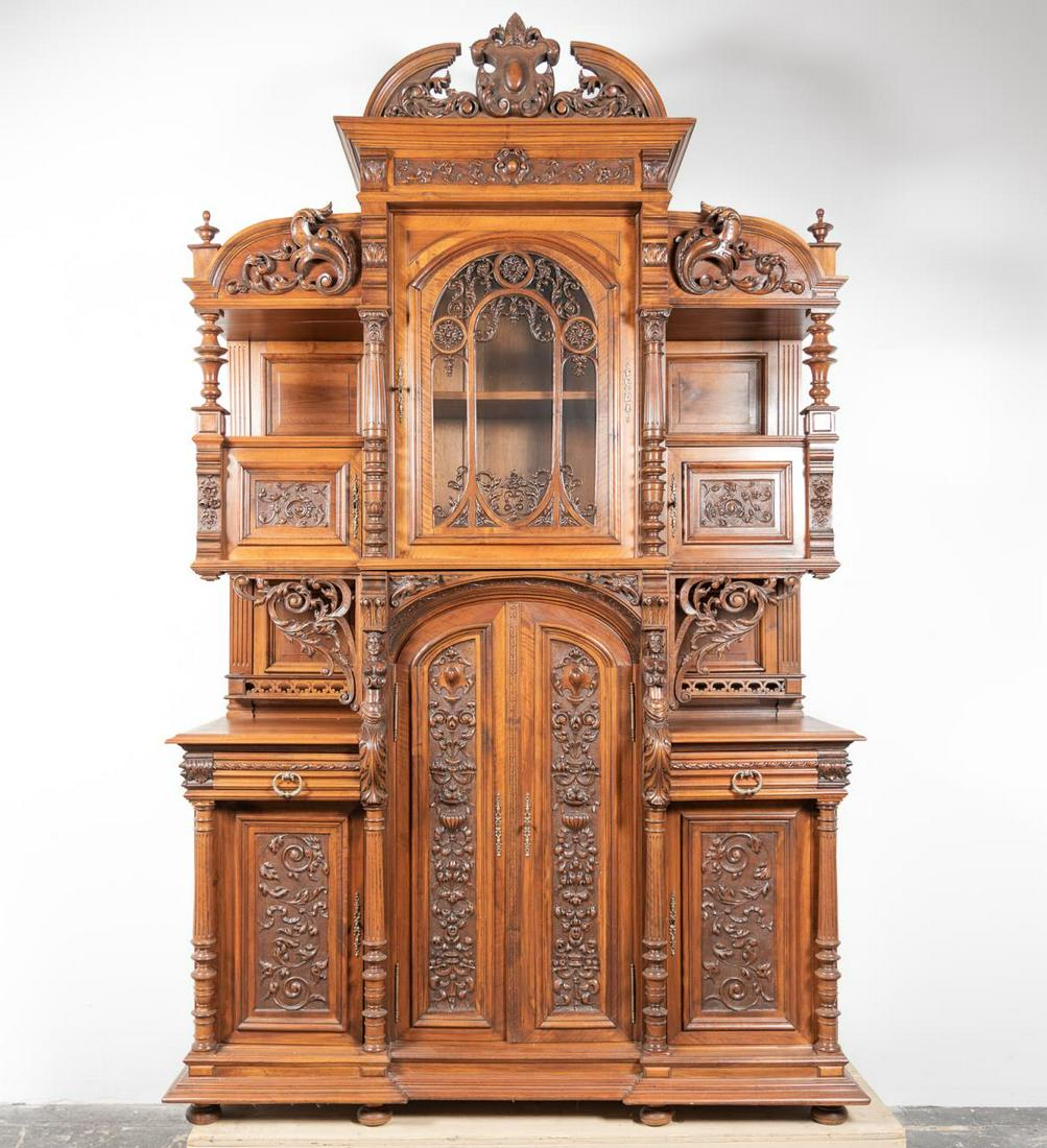 Monumental Henri II Walnut Buffet A Deaux Corps: Late 19th century, Continental; walnut case in two parts; in the renaissance taste; foliate carved broken pediment with a central cartouche; the central section having a pierced arched foliate carved 