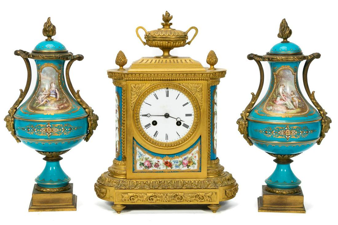 19th C. Continental Sevres Style Garniture Set: Continental , late 19th to early 20th century. Three-piece gilded bronze mounted porcleian garniture set in the Louis XVI Sevres manner comprising a clock surmounted by an urn and a pair of handle-les