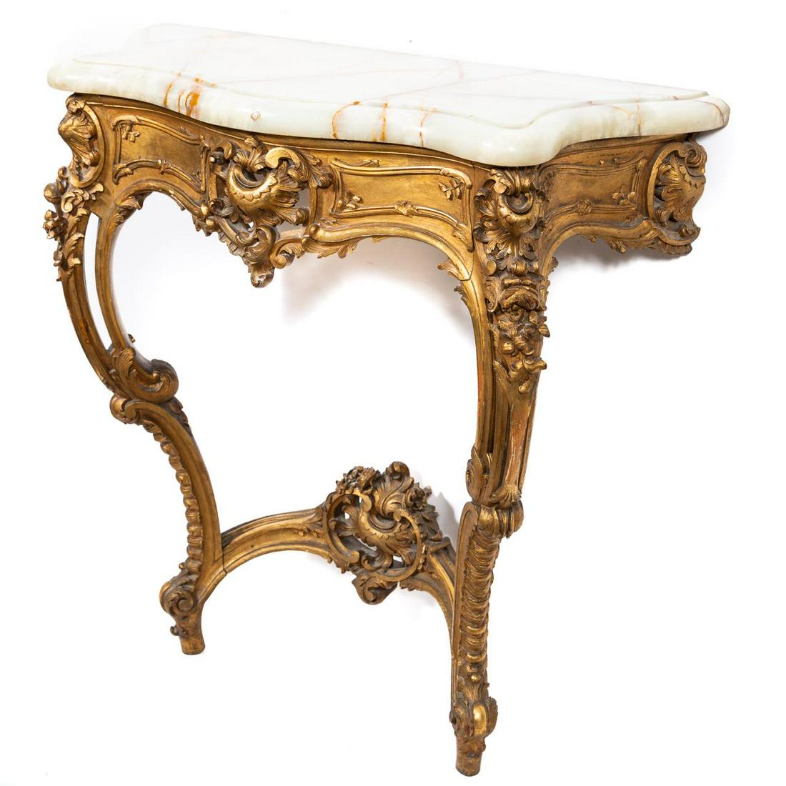 19th C. Louis XV Style Giltwood and Onyx Console: Likely Continental, late 19th to early 20th century. Giltwood wall mounted console table in the Louis XV rococo taste having a shaped, serpentine onyx top, the conforming base with scrolled apron, and