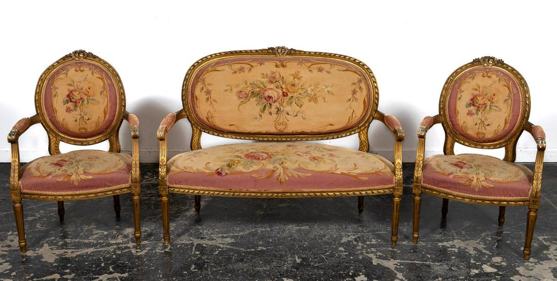 Three Piece, 20th C. Louis XVI Style Parlor Set: French, early 20th century. Louis XVI style with gilt floral & ribbon motif frames, Aubusson type floral tapestry upholstery, consisting of two open armchairs and an open arm settee. Approx. h. 37.5",