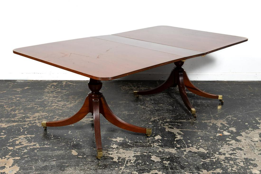 Federal Style Mahogany Pedestal Dining Table: American, 20th century. Mahogany double pedestal dining table with two leaves in the Federal taste having a reeded edge, ringed pedestals and rising on upswept fluted legs with brass caps with casters