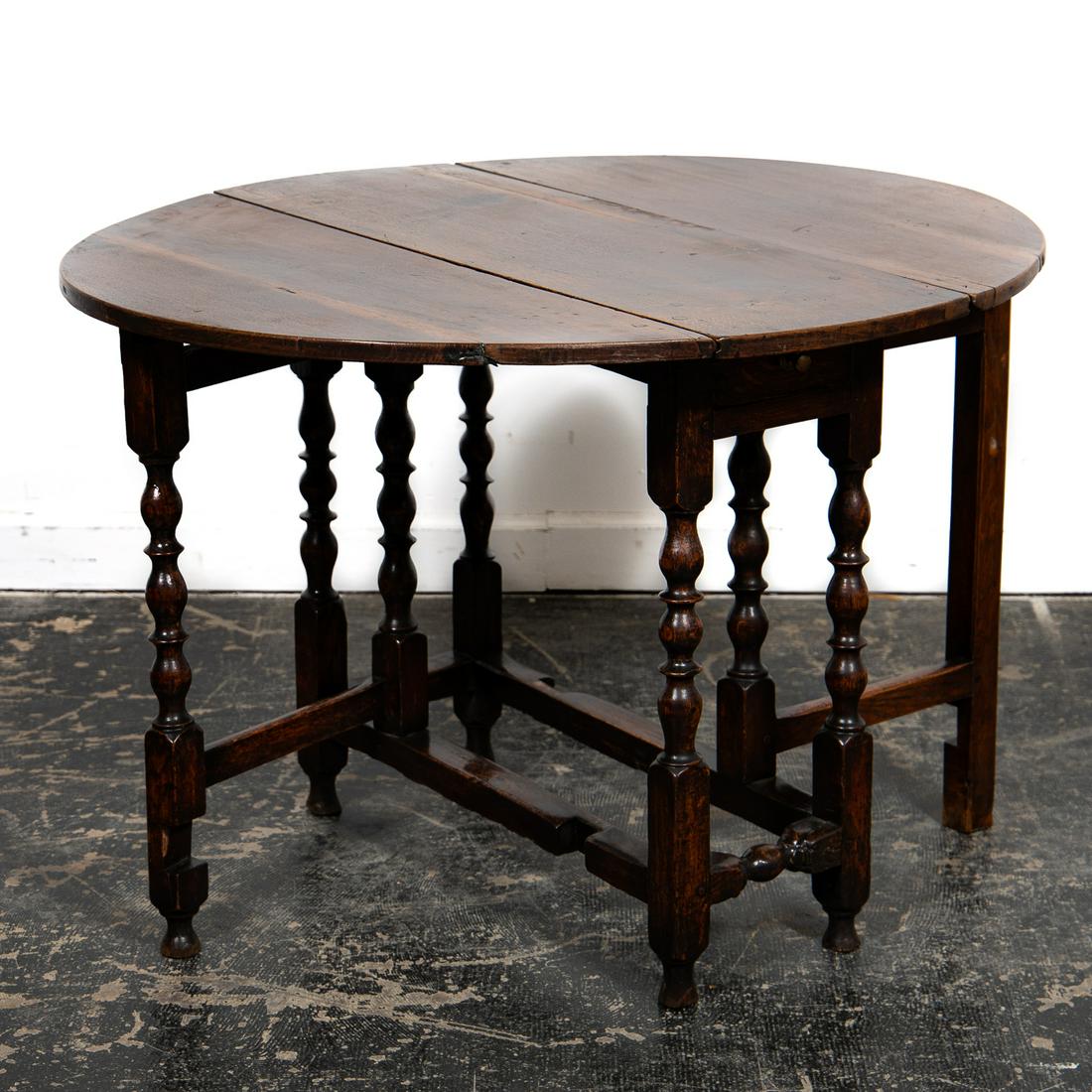 William & Mary Style Stained Oak Gate Leg Table: American, late 19th century. A William and Mary style dark stained oak gate leg table having turned legs, two drop leaves and center drawer. Approx. 28", w. 12.5", d. 35.25", width of one side leaf 14