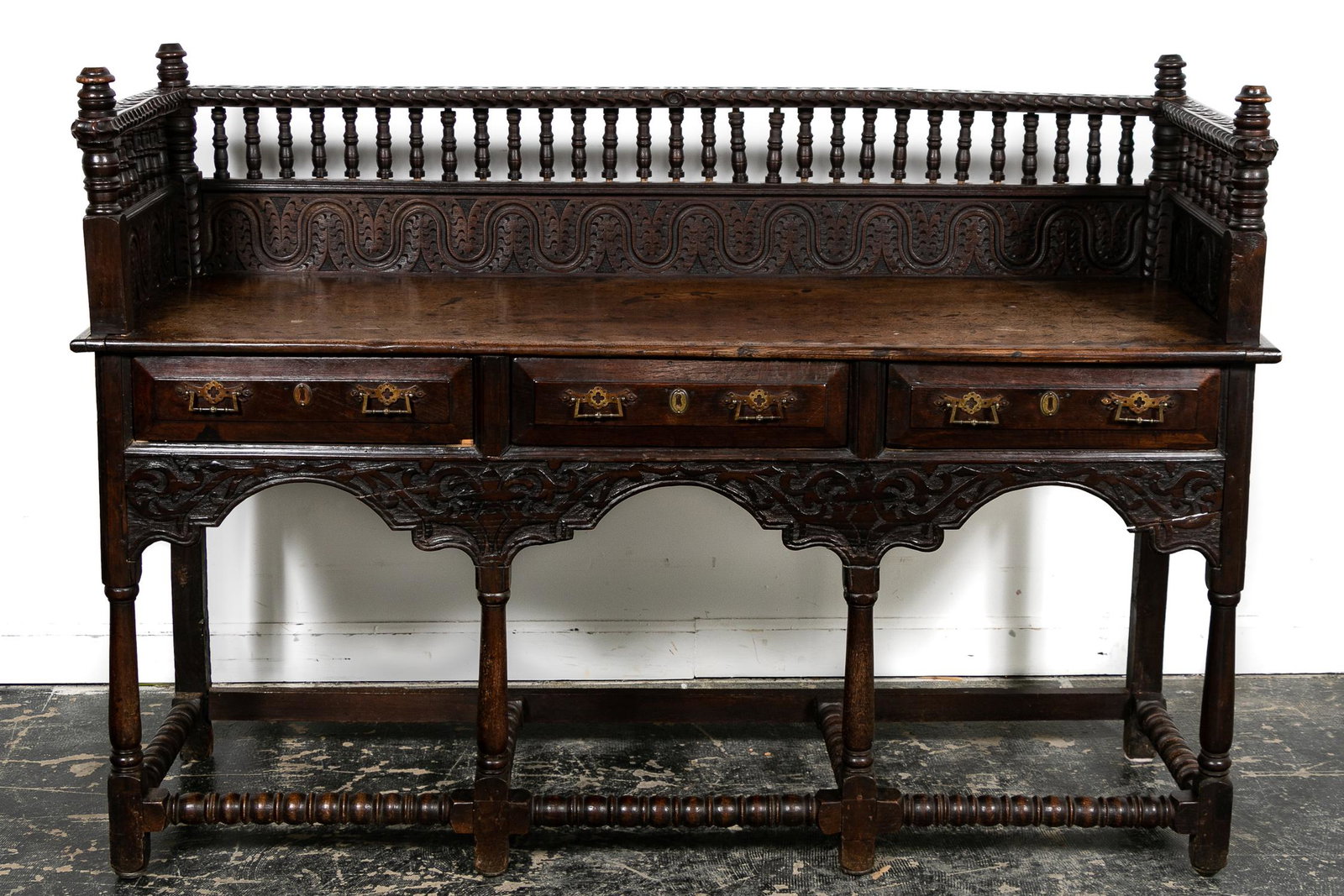 19th Century, Carved Oak Antiquarian Server: English, 19th century. Elaborately carved Victorian era oak server or sideboard in the antiquarian gothic taste having a spindle decorated backboard with turned finials, three beveled drawers, column 