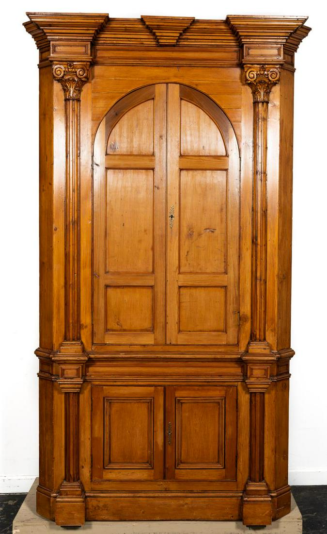 English Georgian Style Waxed Pine Corner Cabinet: English, early 20th century. Tall pine corner cabinet or cupboard having a shaped cornice supported by composite order columns, double paneled doors that open to reveal two scalloped shelves, the lowe