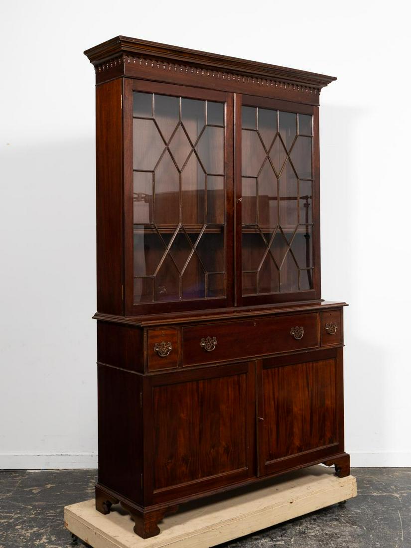Georgian Style Mahogany Butler's Desk Bookcase: American, 20th century. Mahogany bookcase in the Georgian-Chippendale taste, in two parts, having a shaped cornice with arched detail, double astral glazed glass doors, the fold-down butler's desk wit