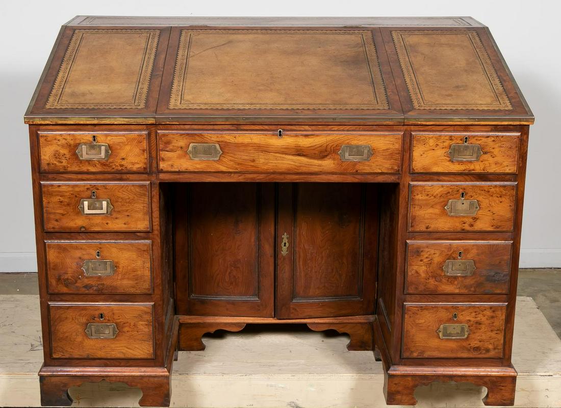 19th English Elm Campaign Desk: English, 19th century. Paneled elm desk, finished on all sides, having a slant front writing surface with tooled leather that lifts to reveal a compartment with open storage compartments, with three f