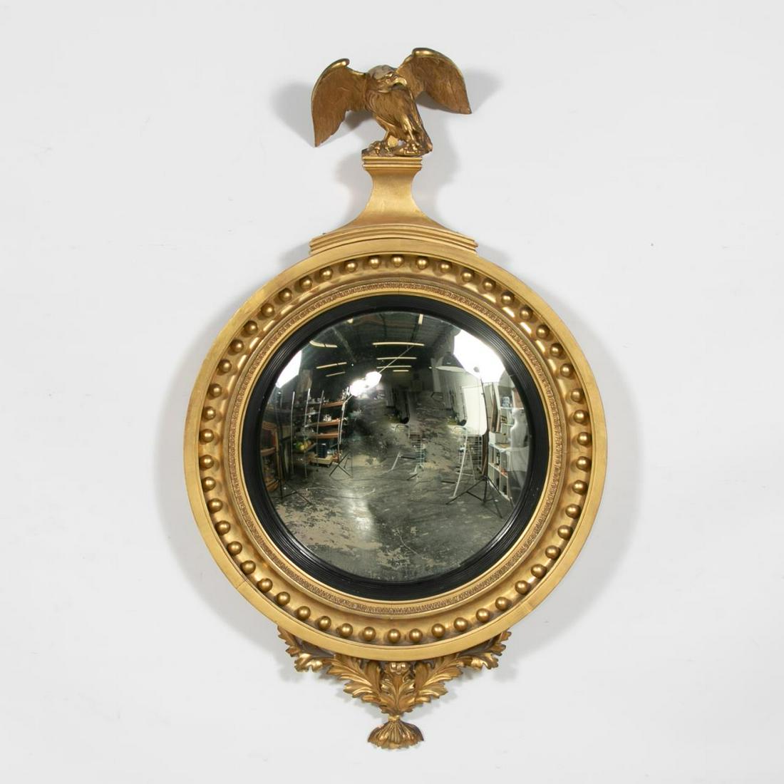 19th C. English Giltwood Convex Mirror: English, first quarter 19th century. Regency era giltwood convex or bullseye mirror surmounted by an eagle on a rocky mount, the frame with spherical elements and ebonized inner fillet, terminating on