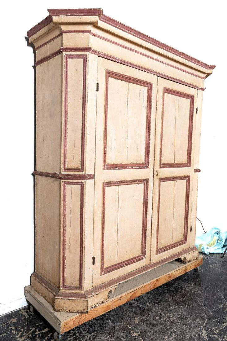 Large Continental Polychrome Distressed Cabinet: Continental, 19th century. Large wooden cabinet or wardrobe, having red and cream decoration, shaped cornice, double doors, the interior fitted with a single shelf and rising on black feet. Unmarked. 
