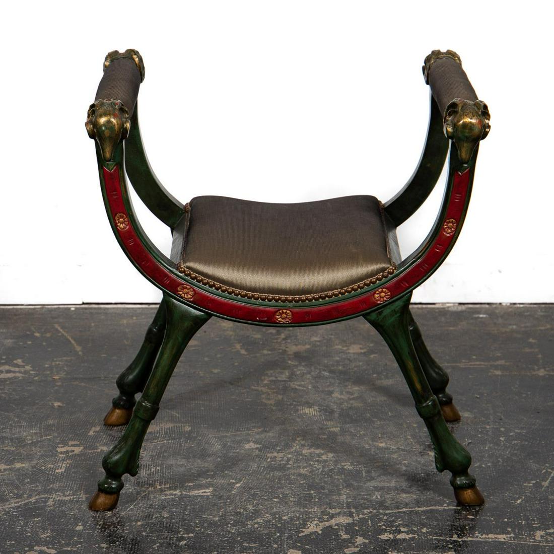 Italian Polychrome Ram's Head Curule Bench: Likely Italian, 20th century. Carved and polychrome, part-gilt decorated wooden bench in the neoclassical taste having ram's head arm rests, upholstered seat and rising on hoof feet. Unmarked. Approx.