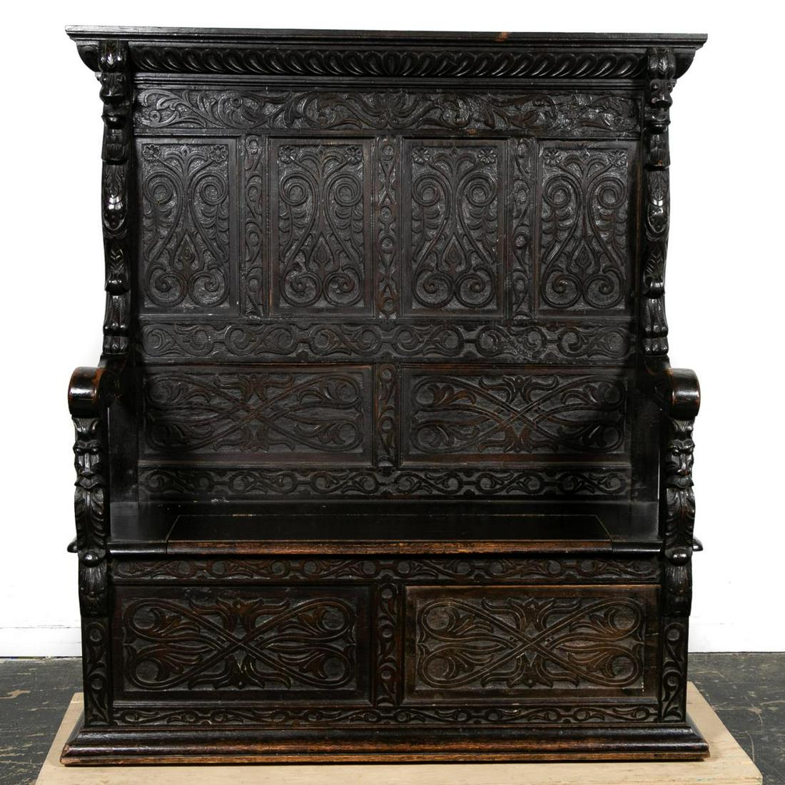 19th Century, Carved Oak Antiquarian Hall Settle: English, 19th century. Elaborately carved Victorian era high-back oak hall settle or bench in the antiquarian gothic taste, having a shaped cornice supported by leopards, flanking scrolled and foliate