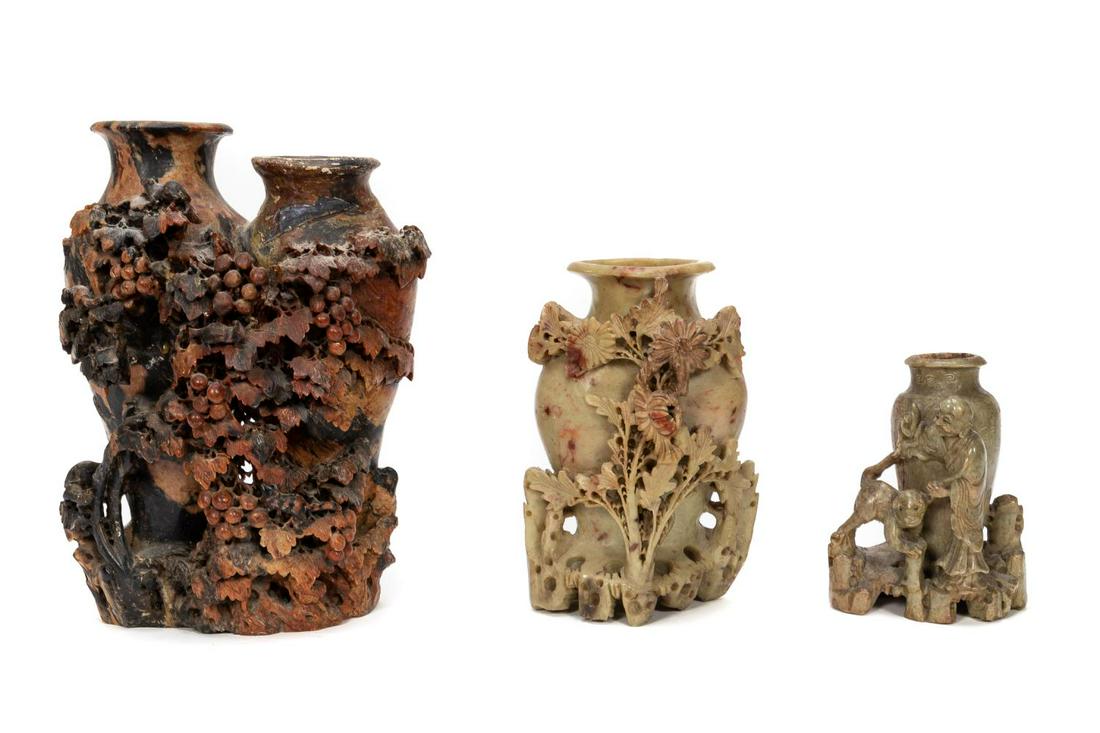 THREE CHINESE CARVED SOAPSTONE URNS: Chinese. Group of three carved soapstone urns comprising one large grape patterned urn, a foliate patterned grey-green urn and a smaller figural grey-green one. Unmarked. Approx. of the largest 10.5",