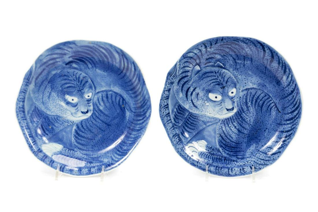 PAIR, JAPANESE ARITA PORCELAIN TIGER MOTIF PLATES: Japanese, probably Meiji period. A pair of blue and white footed porcelain plates with a tiger motif to the surface, scalloped edges and wave forms to the underside. With a "Fu Ku" style mark to the u