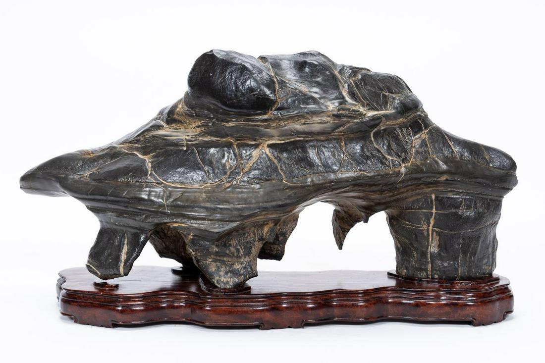 AFRICAN SCHOOL ABSTRACT SHONA STONE SCULPTURE: African School. Abstract sculpture - late 20th century, carved and polished black shona stone sculpture, apparently unsigned. Naturalistic sculpture on a wooden stand. Approx. h. 13.25", w. 24", d. 7"