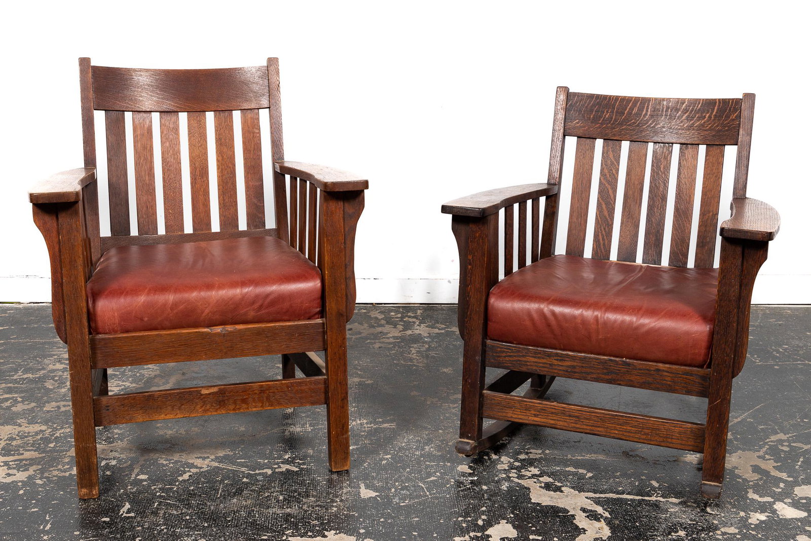 20TH C. ARTS & CRAFTS MISSION OAK CHAIR AND ROCKER: American, early 20th century. A group of two oak mission arts and crafts chairs in the manor of Stickley. Comprising of one arm chair and one rocking chair. Apparently unmarked. Approx. h. 36", w. 28.