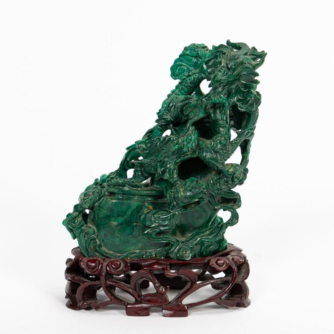 CHINESE, CARVED MALACHITE DRAGONS FIGURE ON STAND: Chinese. Carved malachite figure depicting two batting dragons, affixed on a wooden stand. Unmarked. Approx. overall h. 6”.